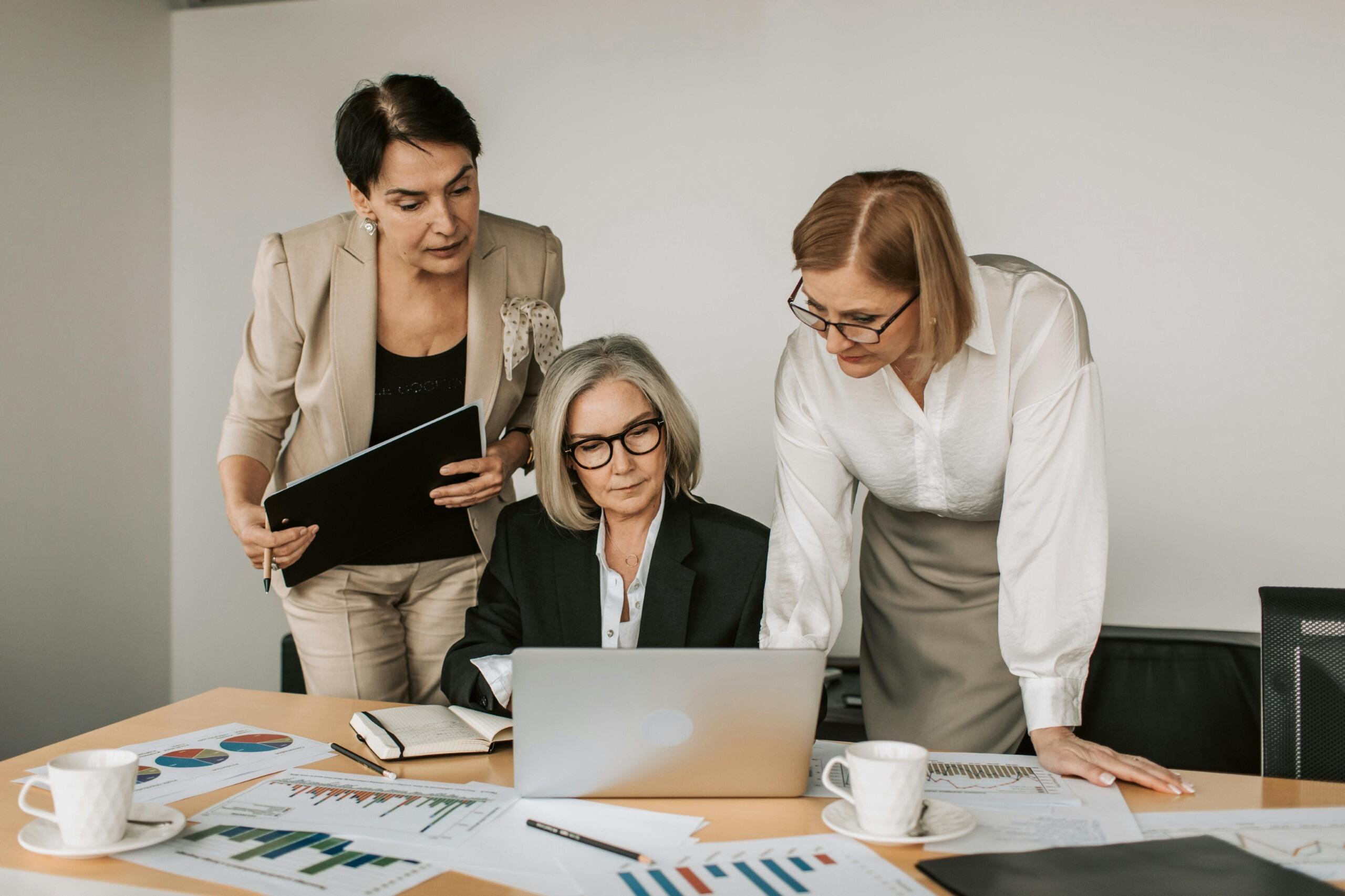 Three businesswomen collaborating at a desk with charts.