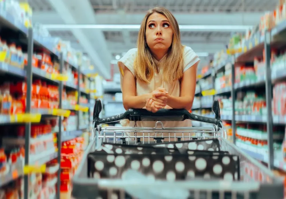 Woman pushing trolley down a supermaket aisle