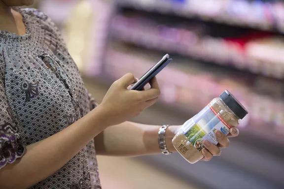 Woman scanning a barcode of a product with her mobile phone in a supermarket