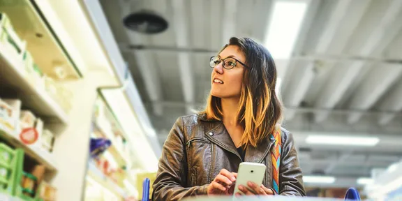 Woman looking at products with her mobile phone in her hands in a supermarket