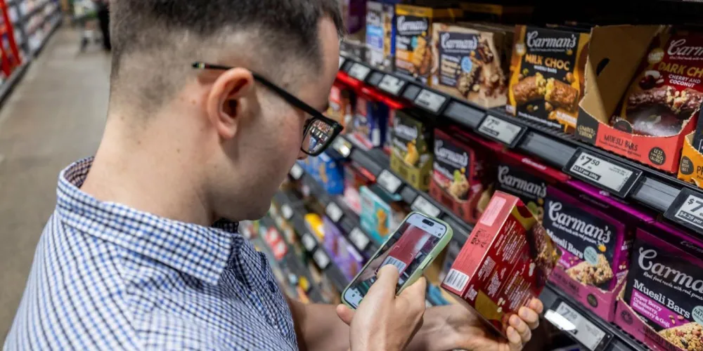 Man scanning barcode on a box of muesli bars in a supermaket