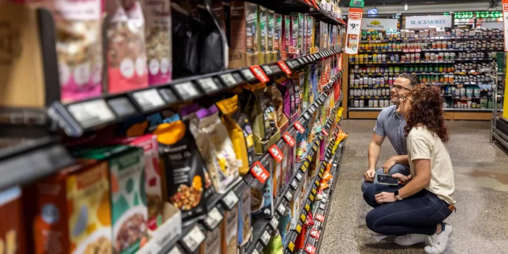 Man and woman crouching and looking at supertmarket shelves
